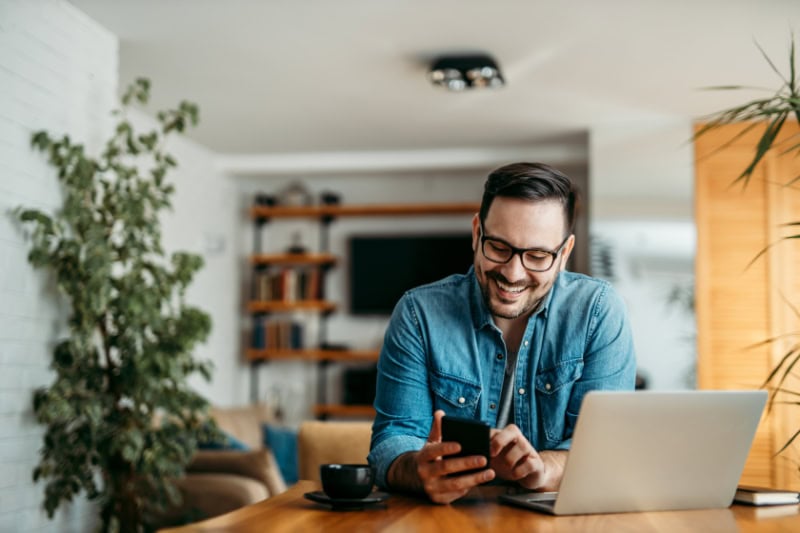 AC Maintenance Checklist. cheerful man using smart phone at home office.