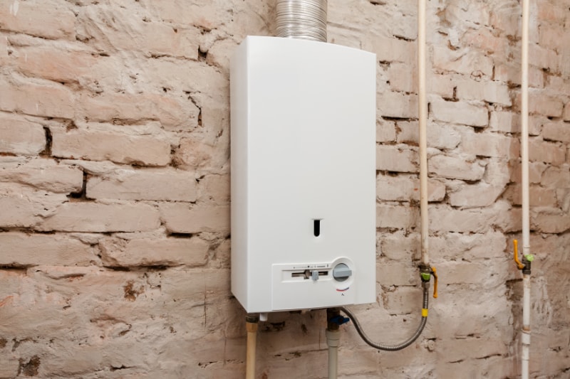 Gas boiler in boiler room for hot water on a beige brick wall.